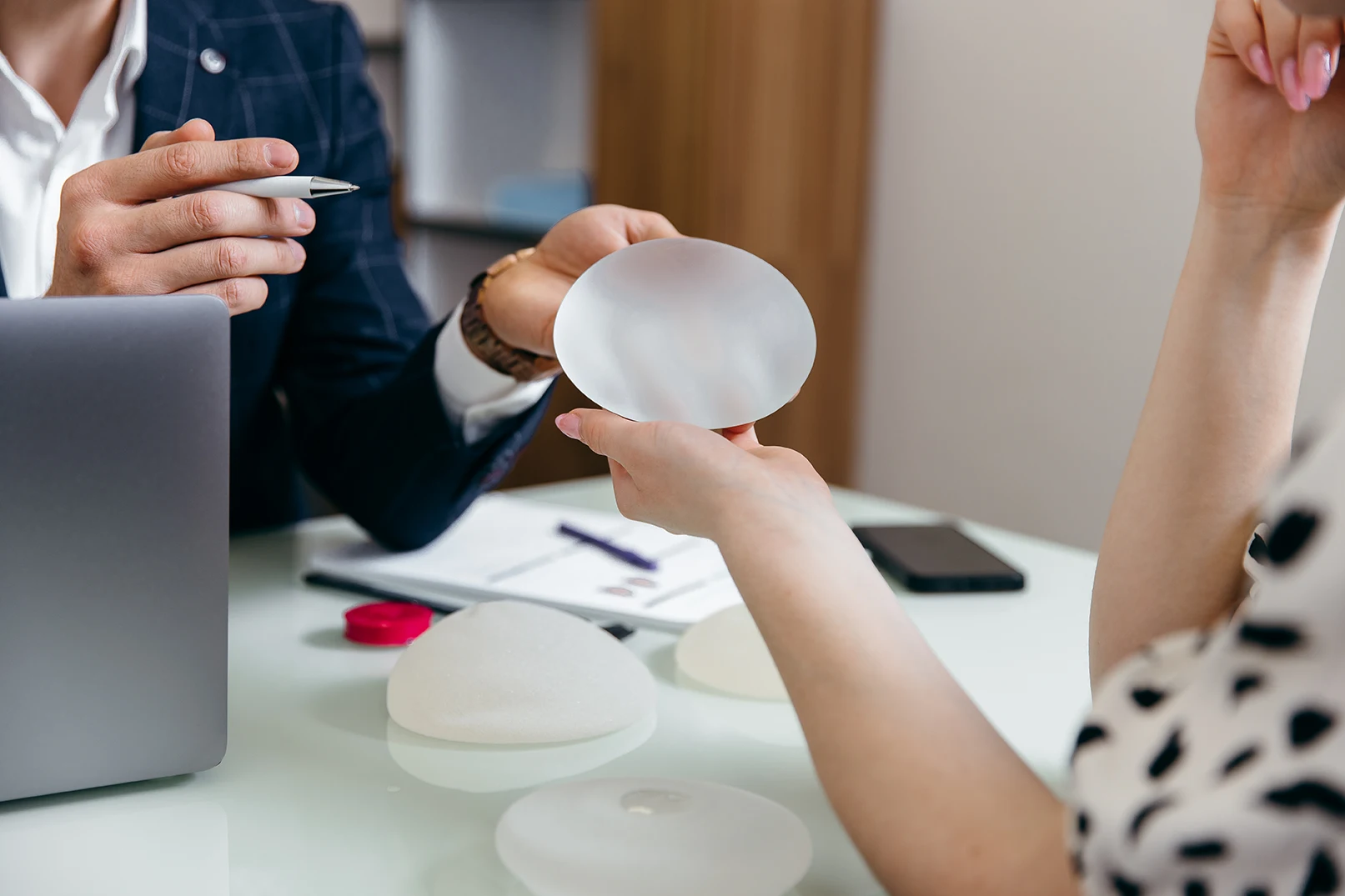 Cosmetic surgeon shows female patient breast implant samples